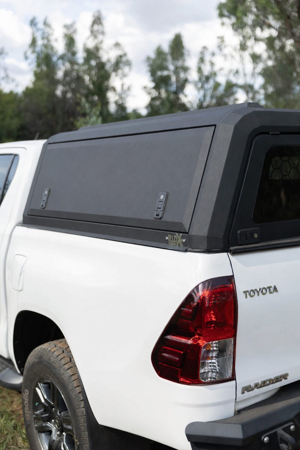 Stainless steel canopy installed on a white Toyota pickup truck, providing weather protection and enhancing vehicle appearance, part of RLD Design's product range.