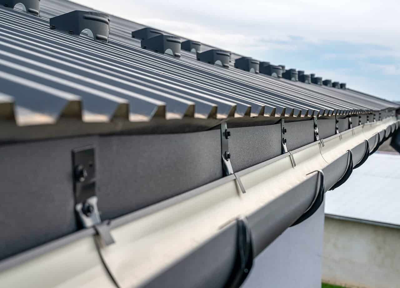 Roofing-for-Troops-Gutter-Cleaning-Services-06 A photo of a roof with a gutter drain installed, advertising Roofing For Troops' gutter cleaning services