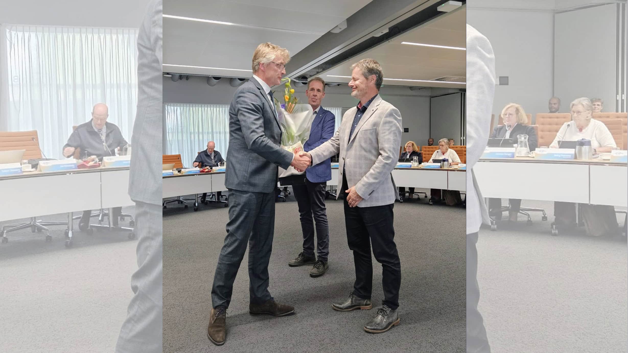 Uitreiking van een bloemenboeket tijdens een formele bijeenkomst bij RTV SLOS.