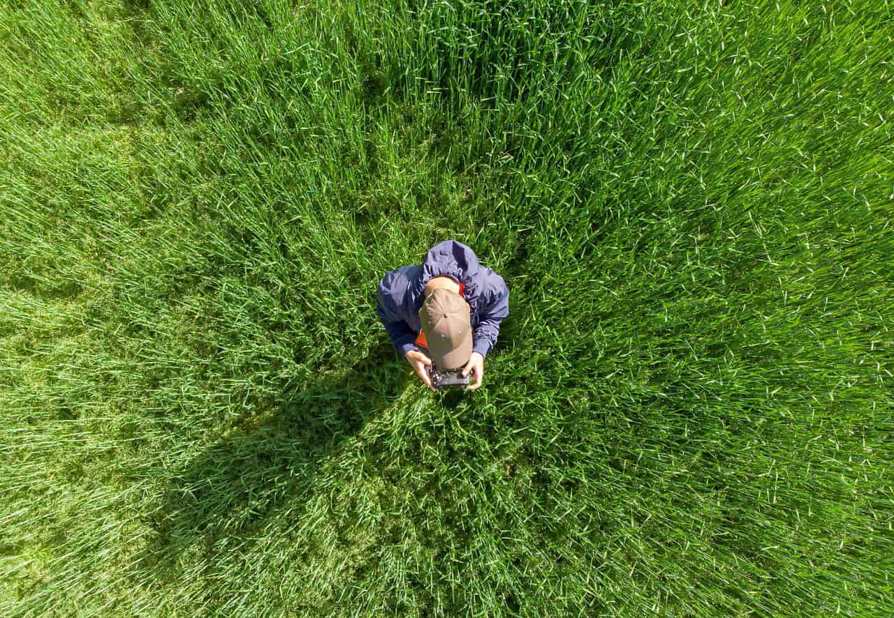 Drone beeld van een persoon in een groen veld die met een remote controle een drone bestuurt, illustratie van drone hobby, fotografie en outdoor activiteiten.