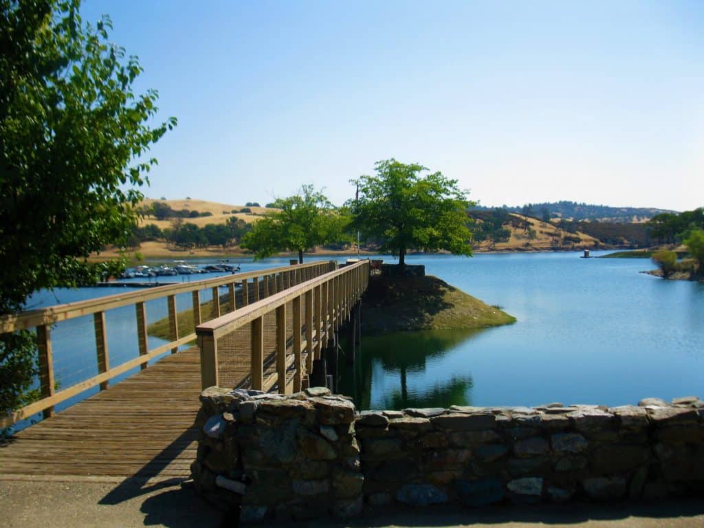 Peaceful lakeside view with a wooden bridge and lush greenery, perfect for outdoor recreation and nature lovers.