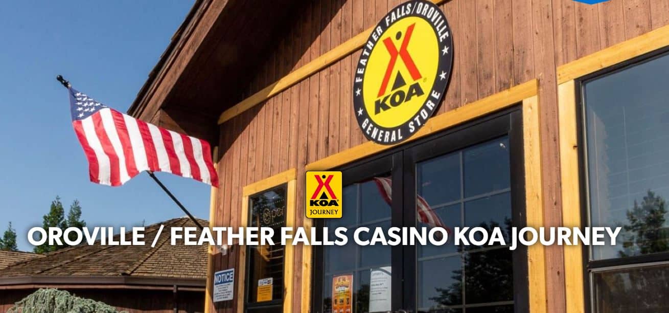 Flag flying outside a KOA Journey campground, Feather Falls/Oroville location with a KOA sign on a wooden building.