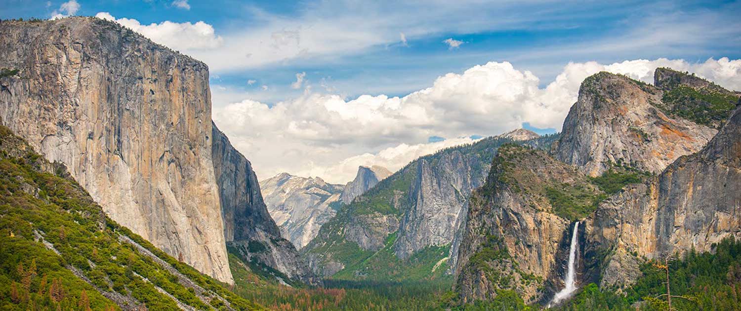 El Capitan and Bridalveil Fall in Yosemite National Park with lush green trees and a dramatic mountain landscape.