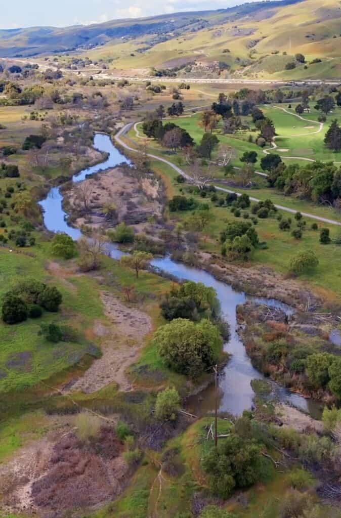 Serene coastal hills with winding river, lush greenery, and scenic bike trails ideal for outdoor recreation and cycling adventures at FreeWheelers.