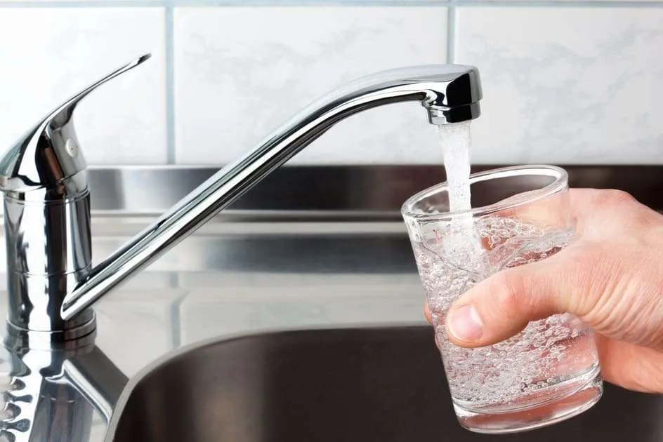 Water poured into glass cup from kitchen faucet