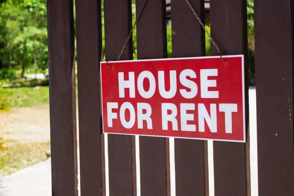 House for Rent sign on wooden picket door