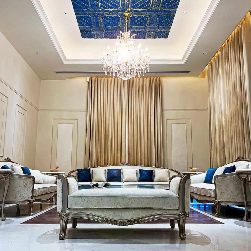 Elegant luxury living room with chandelier and gold drapery, featuring Sak Designs x Space Bound collaboration.