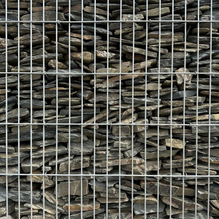 Stos kamieni na składzie z metalową siatką zabezpieczającą.