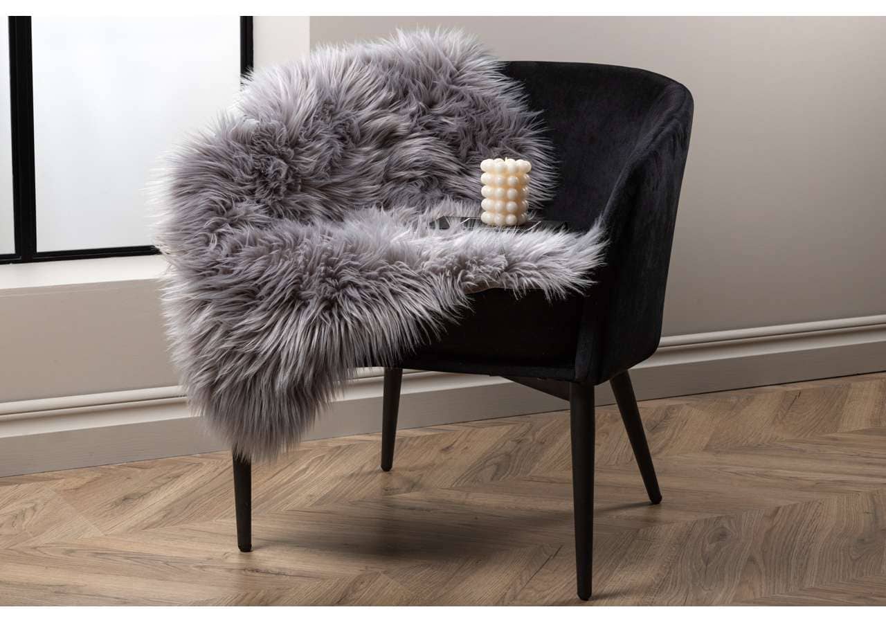 Långhårig fårskinnsfilt på svart stol, inredning, lyx, mys.