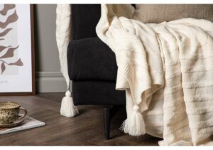 Mysig säng med textilier i beige och svart för ett inbjudande sovrumskänsla.