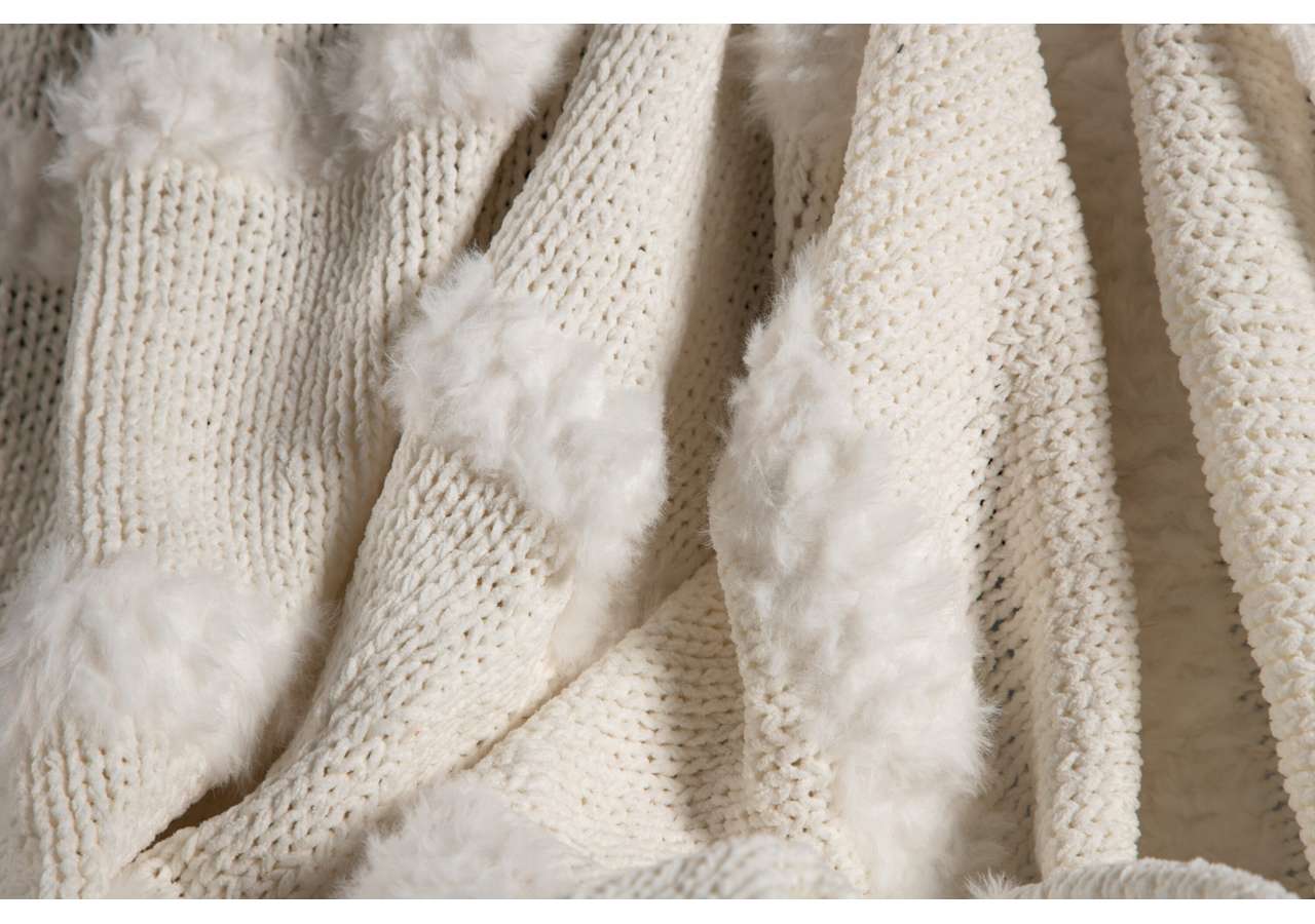 Ljus cremefärgad stickad filt med fluffiga kanter, perfekt för säng och heminredning.