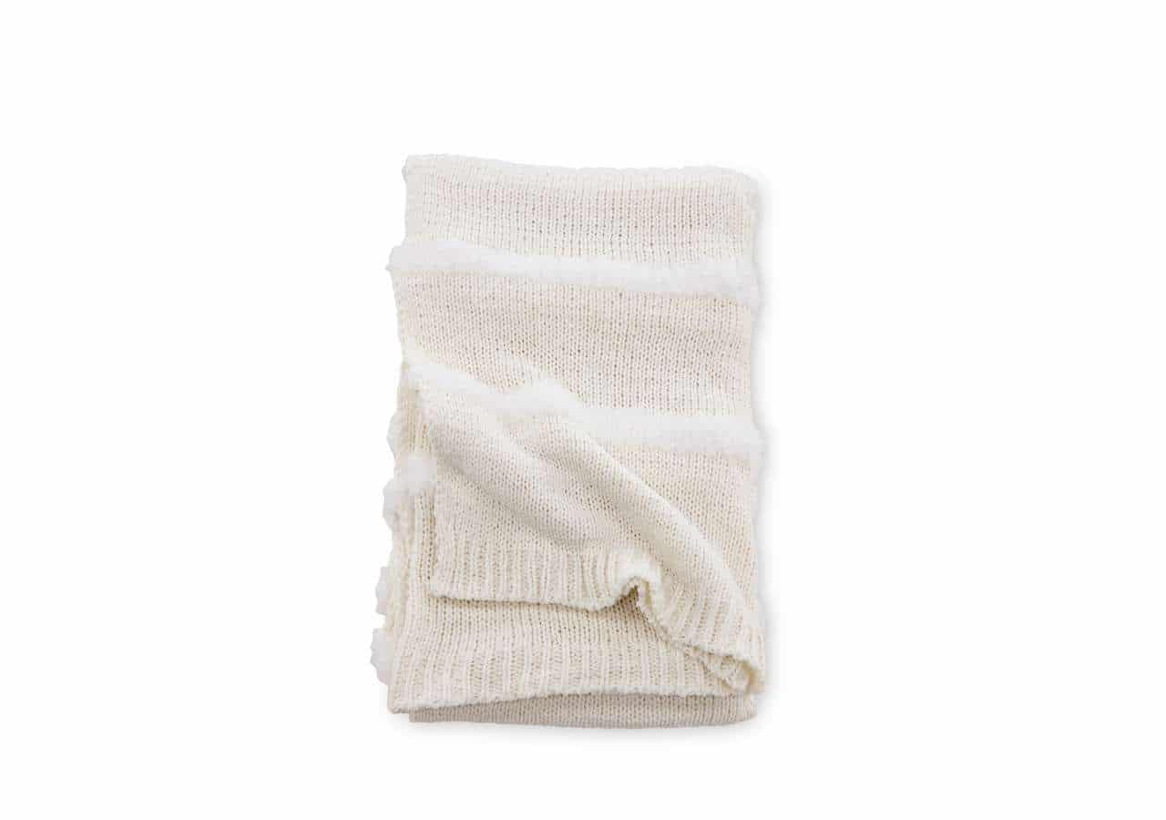 Mjuk-hemtrevlig stickad sängfilt i naturliga toner, perfekt för komfort och stil.