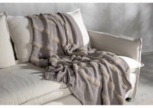 Mysig ullfilt på vit soffa med kuddar, stilfull och varm inredningsdetalj.