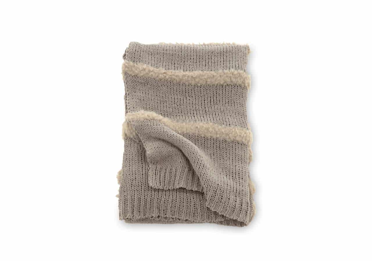 Mjukt ullpläd i beige med randmönster och fransar för mysiga sovrumsmiljöer.