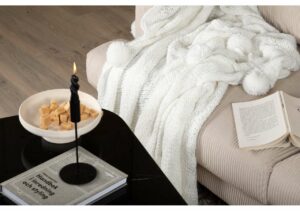Mjukt vit täcke som ligger på en soffa, skapar en mysig hemkänsla.