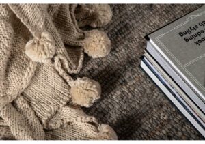 Mjuk ullfilt med pom-pom detaljer på tyst noga matta, perfekt för en skön sovmiljö.