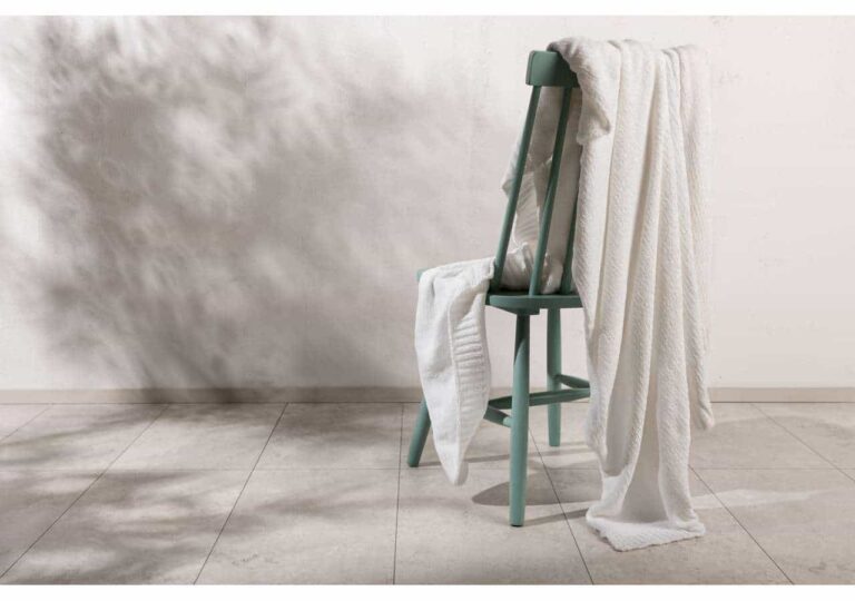 Ljus, modern stol med vita filtar och topptexturlägg för elegant sovrumsstil.