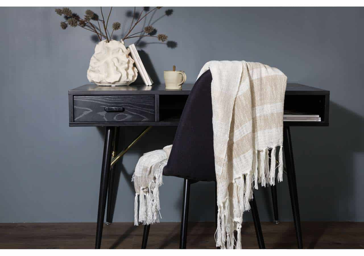 Elegant arbetsplats med mörk skrivbord och mysigt klädd stol, perfekt för hemmet eller kontoret.