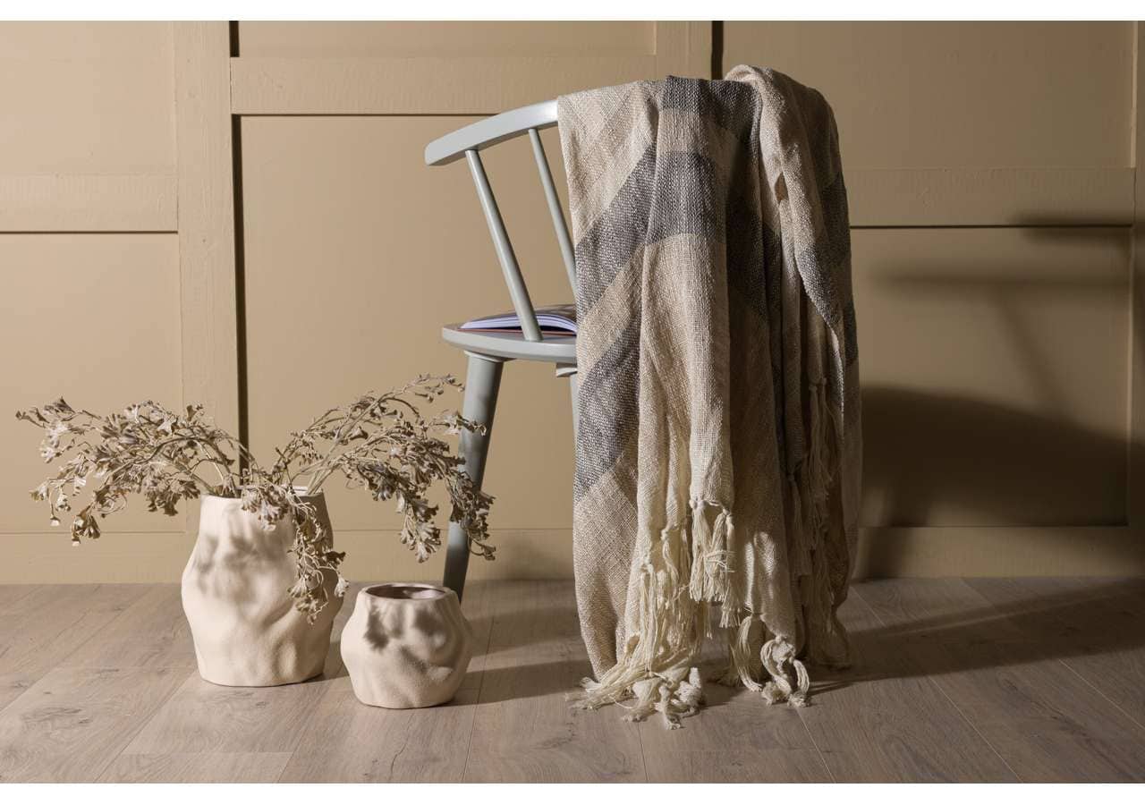 Ljus grå sängram och överkast i beige i en minimalistisk sovrumsstil.