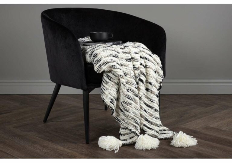 Mörk tylsoffa med vävd filt och bokstöd, elegant samt samlingsplats för avkoppling.