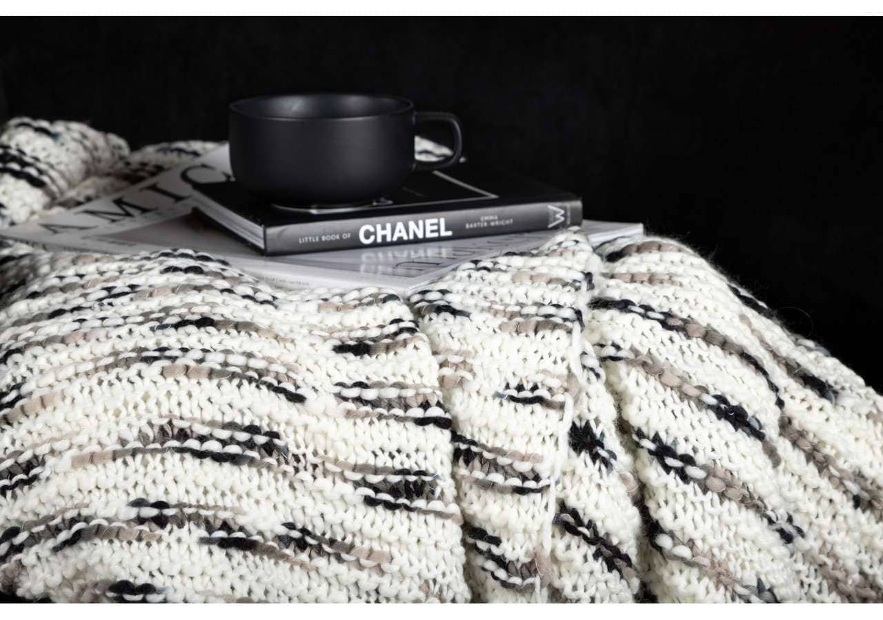Mysig strikkad pläd i neutala färger för exklusiva sängmiljöer.