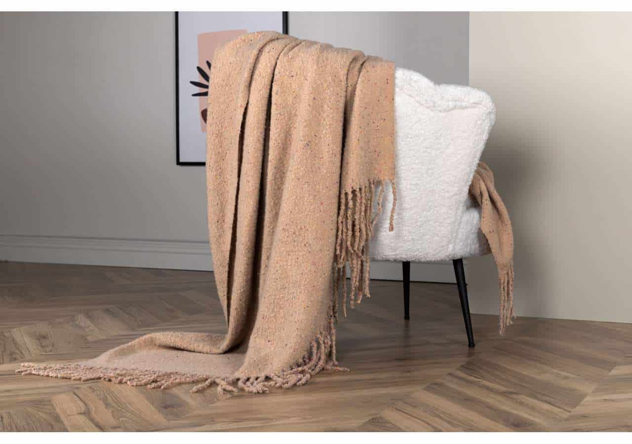 Elegant ullpläd och vit fåtölj i modern inredning, perfekt för mysiga stunder.