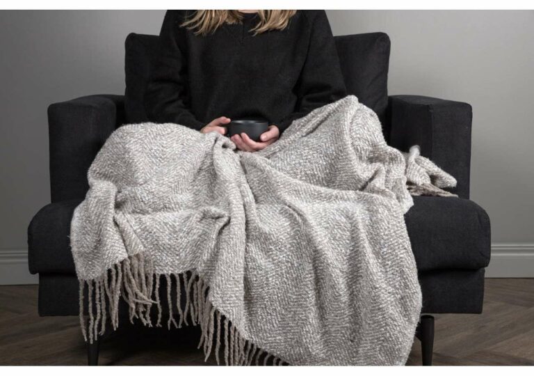 Varm filt och kaffe på svart soffa för mysig vilostund.