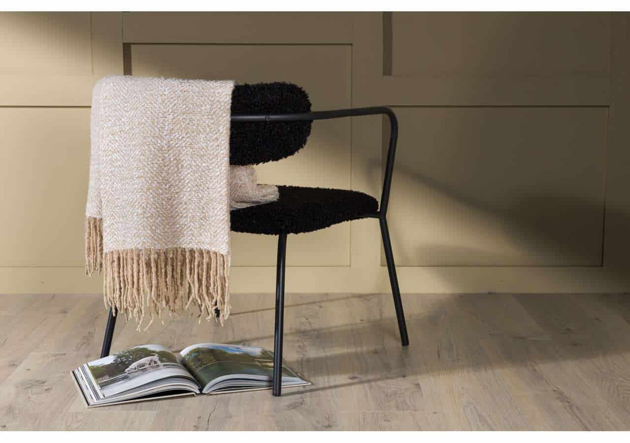 Möbel med textil, svart stol och stickad filt i modernt hem.