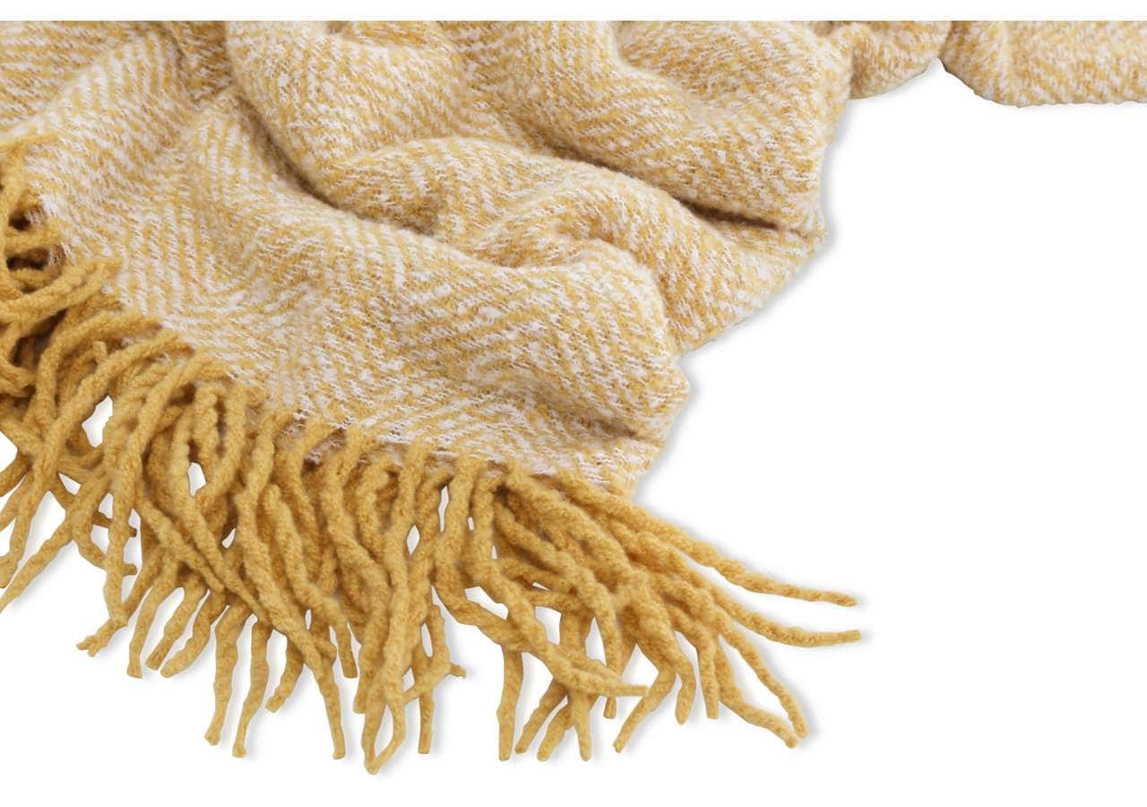 Smutsfritt ullpläd i ljusgul nyans med fransar, perfekt för en mysig sovrumsmiljö.