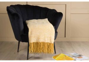 Mjukt gul- och vitrandigt afghan på svart fåtölj, mysig inredningsdetalj från Sängfabriken.