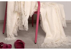 Ljusfärgade, mjuka och lyxiga handdukar hängda på en rosa stol i ett modernt hem.