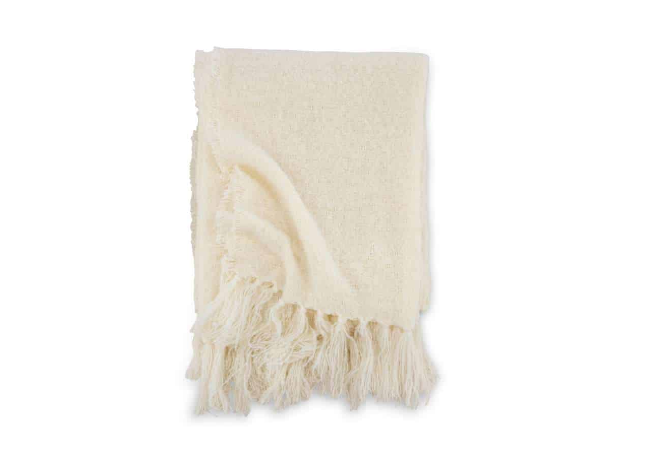 Mjukt och täckande sovpläd i crem färg med fransar, perfekt för sängar och soffor.