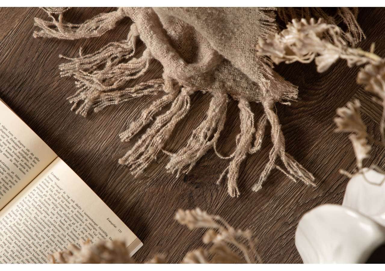 Ullhalsduk i naturfärger på träbord med bok och vaser.