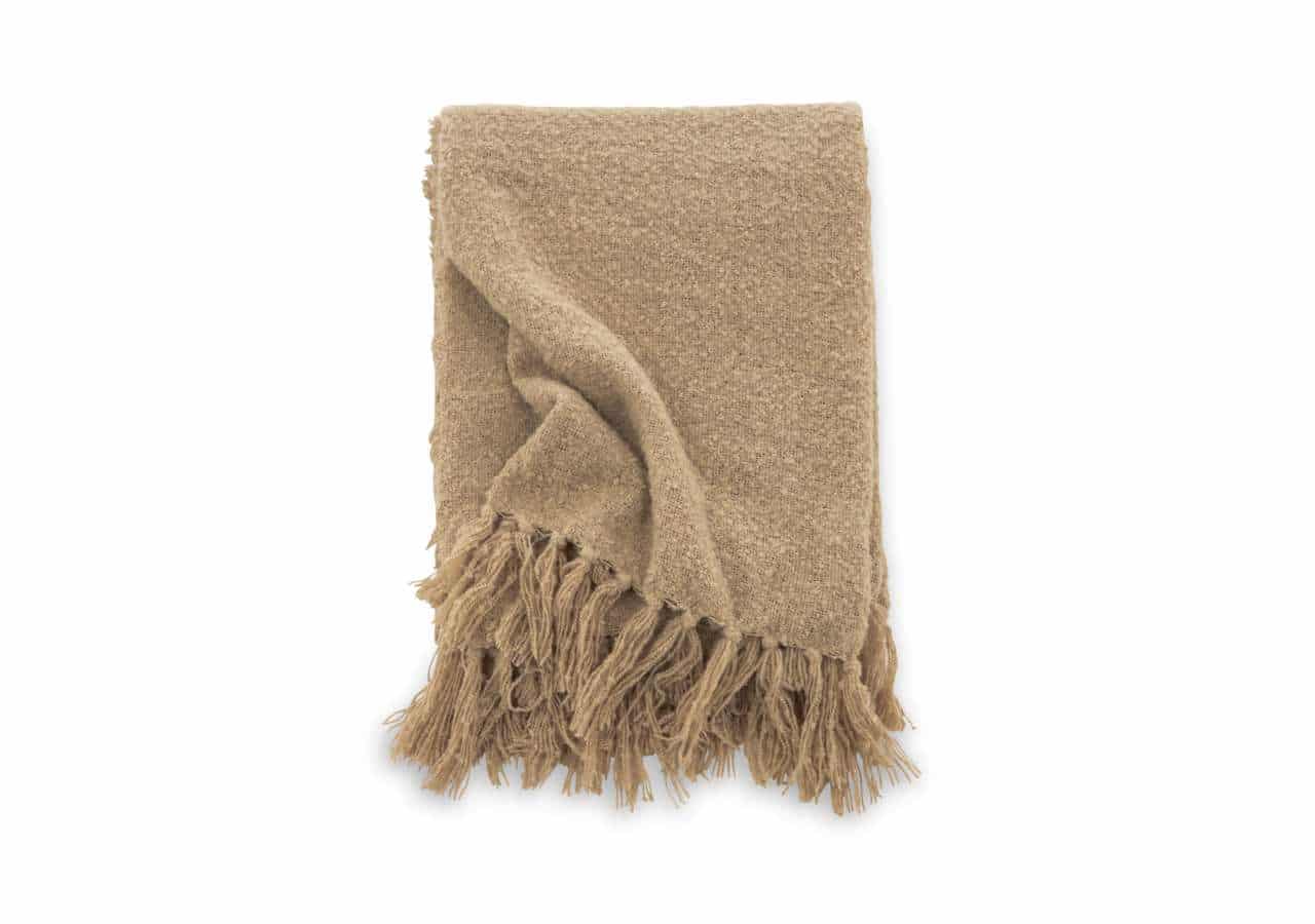 Mjuk beige ullpläd med fransar, perfekt för sovrum och vardagsrum.