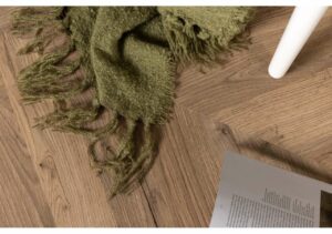 Mjuka, gröna handvävda plädar på trägolv för skandinavisk inredning.