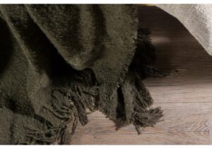 Mjukt, frottévävt, grått täcke med fransar, perfekt för sovrum eller loungemiljö.