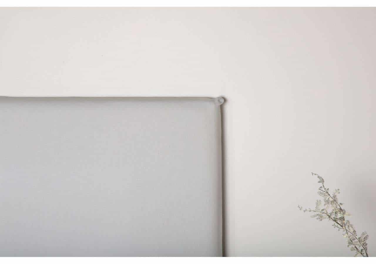 Ljus och minimalistisk sängram i tyg för modern sovrumsmiljö.