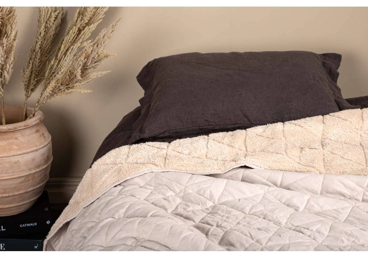 1. Mörkbruna sängkläder och beige bäddmadrass i stillsamt sovrumsmiljö.