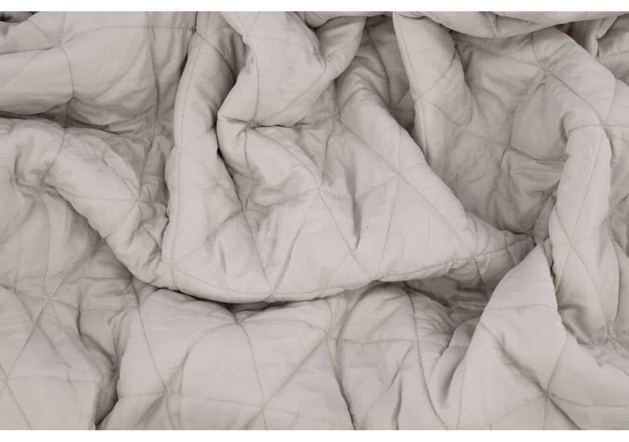 Liggande vit sängmadrass med quiltad masonitnotation och mjuk textur.