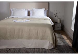 Elegant säng med beige sänggavel och vita kuddar för en sovrumsrenovering.