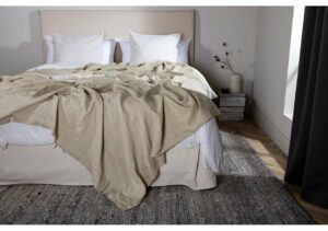 Ljust sovrum med bädd med beige täcke och vita kuddar, perfekt för en bekväm sömntid.