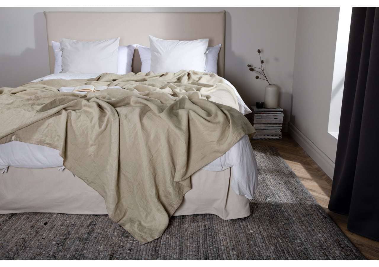 Ljust sovrum med bädd med beige täcke och vita kuddar, perfekt för en bekväm sömntid.