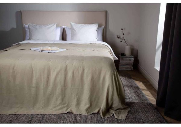 Elegant säng med beige sängtextil och vita kuddar i modern sovrumsstil.