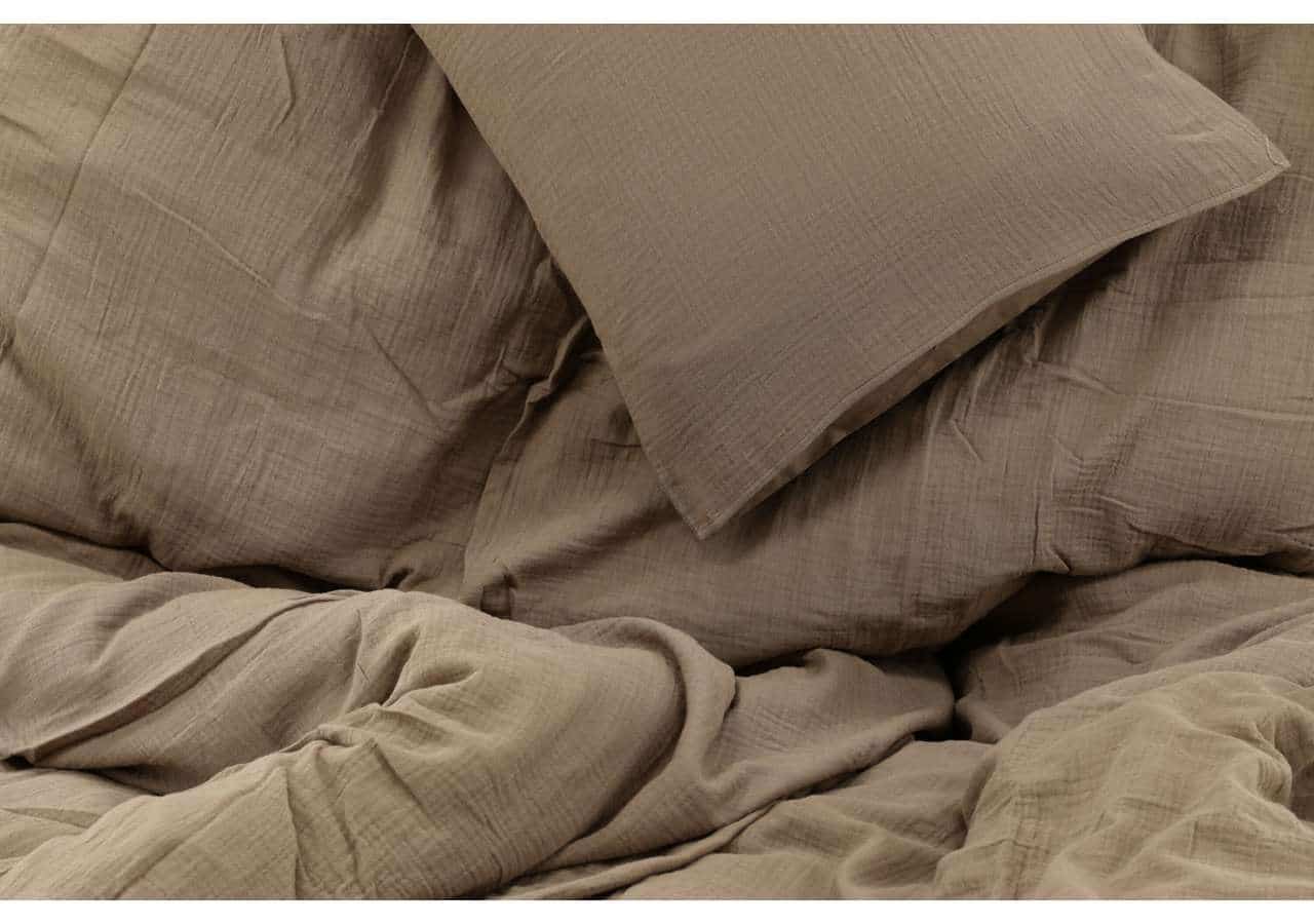 Mysig bädd i beige sängkläder, exklusiv kvalitet för en god natts sömn.