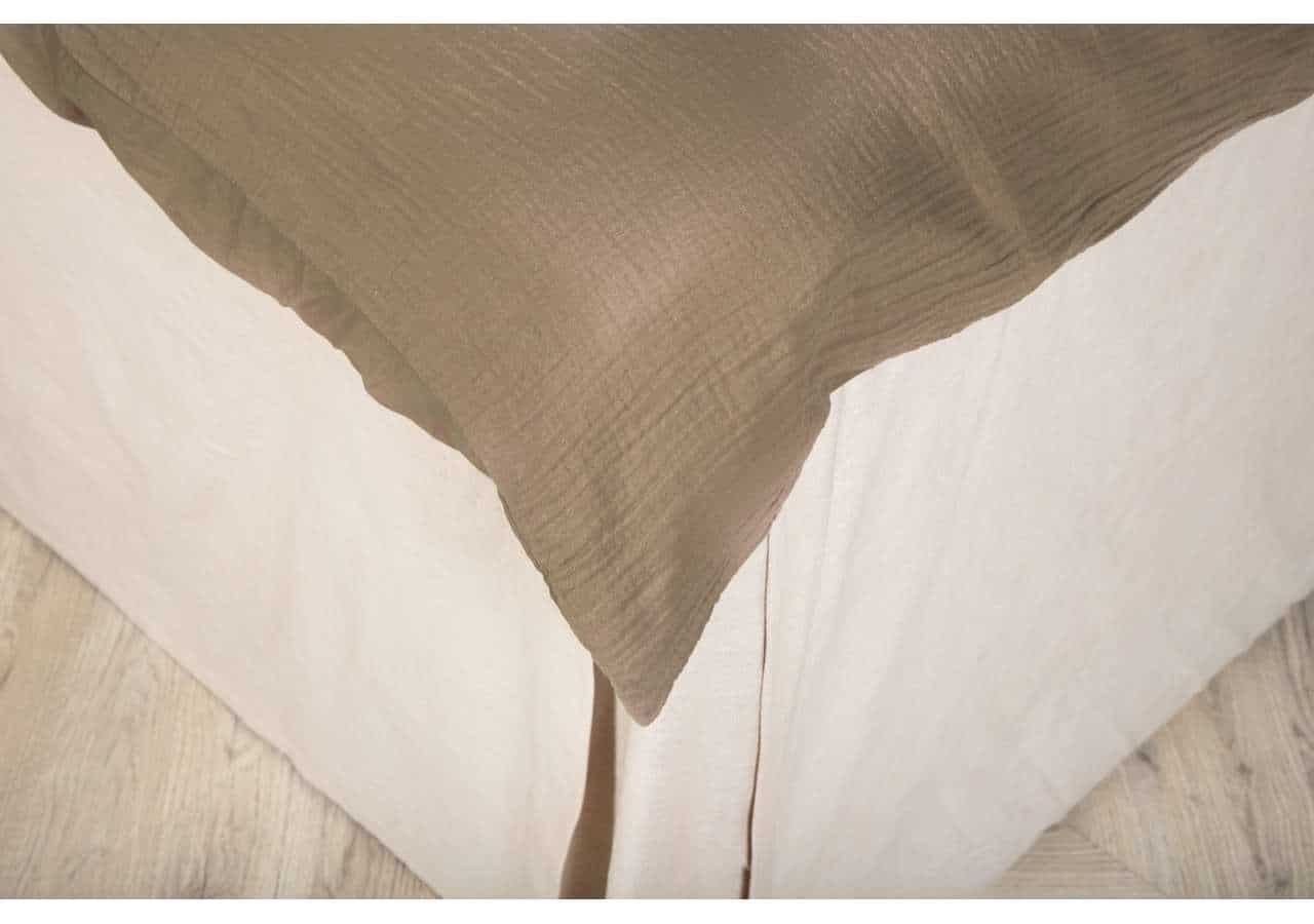 Mjuk beige och vit sängkudde i naturmaterial, elegant och bekväm sovrumsdetalj.