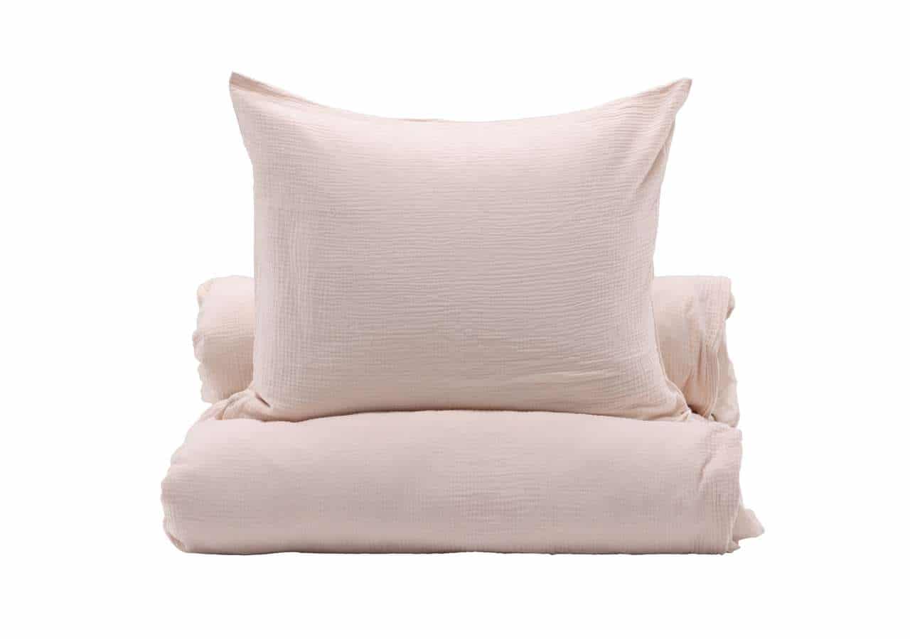 Högkvalitativa sängkläder och örngott i lugnande ljusrosa färg.