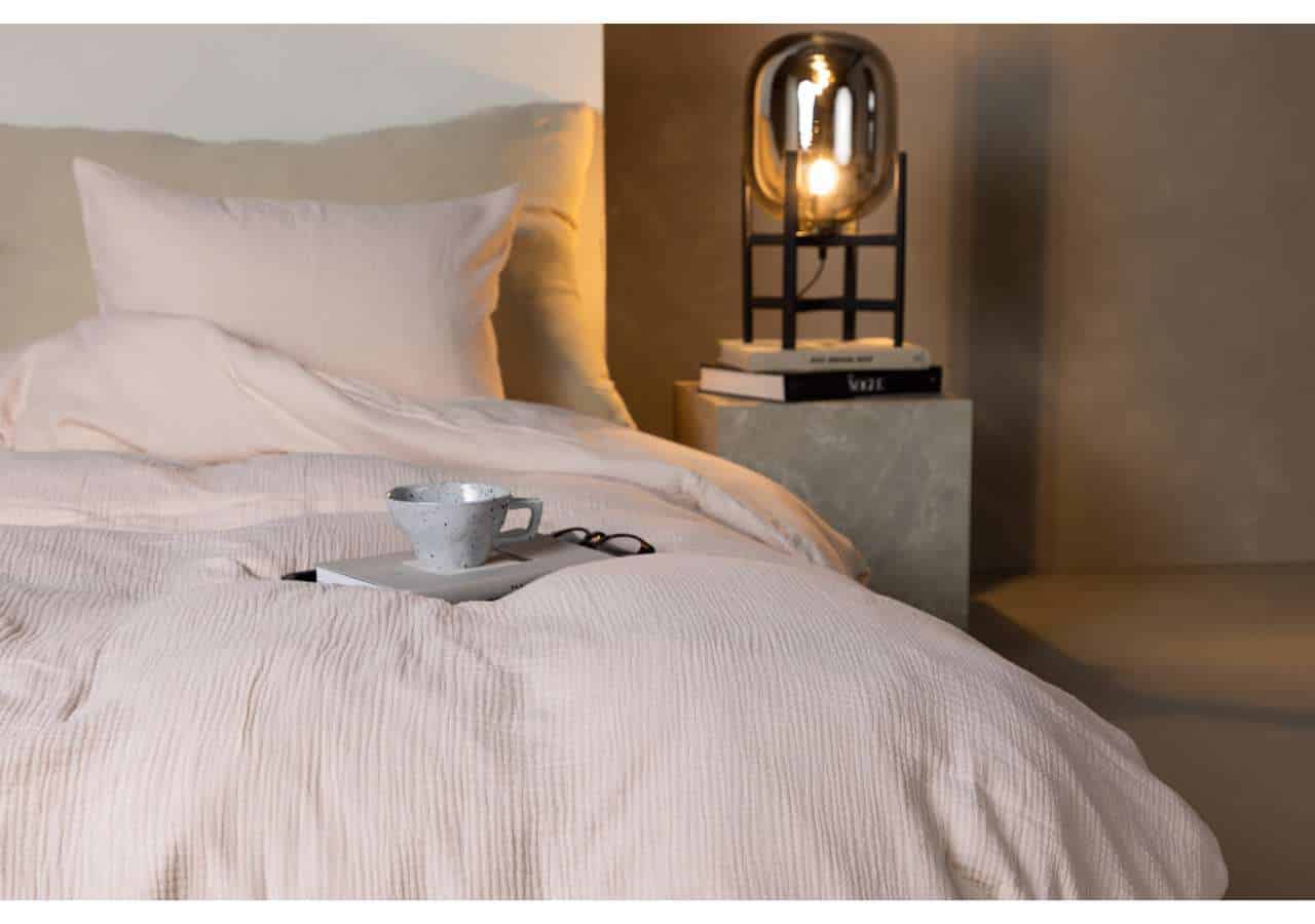 Måttbäddad säng med exklusiva sängkläder i lugn ton, perfekt för avkoppling.