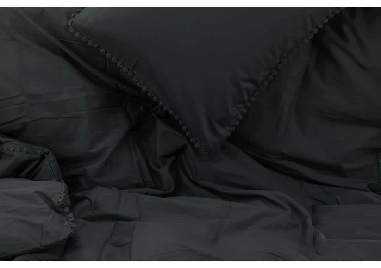 Mörkgrå sängkläder i satin med broderad kant, elegant och mysig inredningsdetalj.