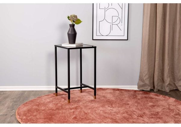 Elegant svart sidobord med blomvas och böcker i modern inredning.