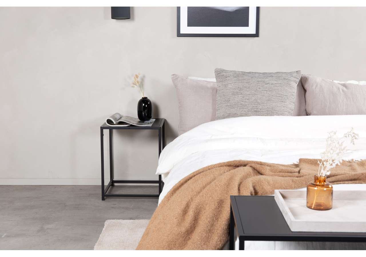 Lätt, stilren säng med mjuka kuddar och pläd i modern sovrumsmiljö.